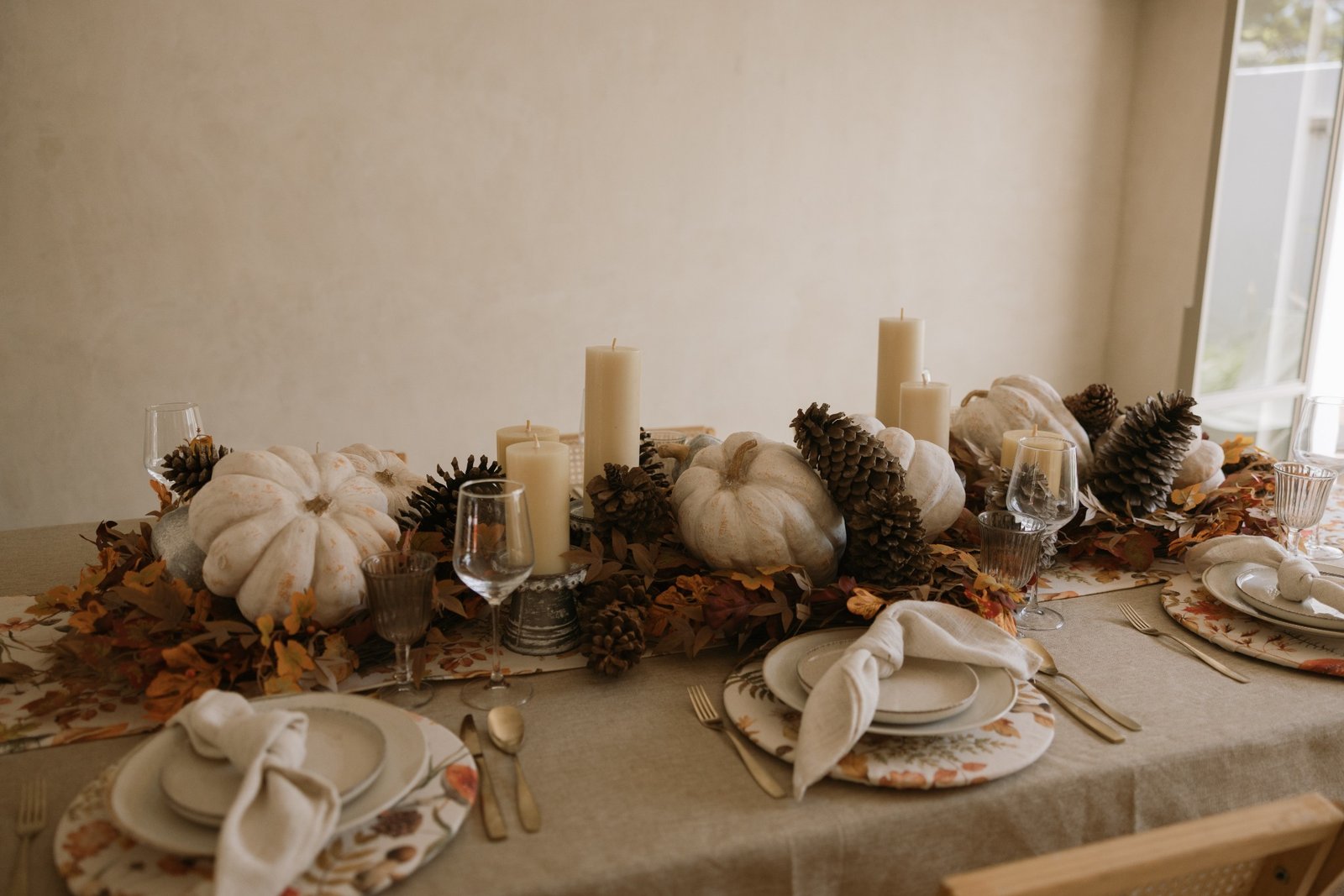Mesa otoñal DEKOR con calabazas blancas, velas y follaje cálido